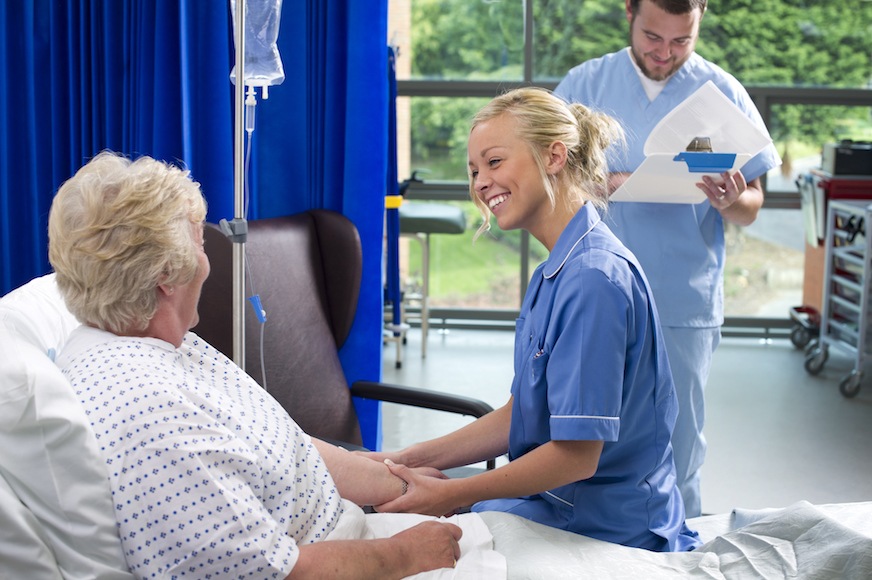 Nurses help an elderly patient with a smile