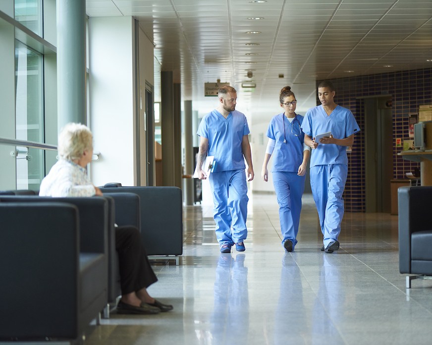 Three nurses walking and talking about patient care