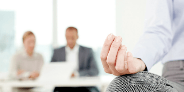 Man's Hand with Fingers Together in Front of Two Business Professionals